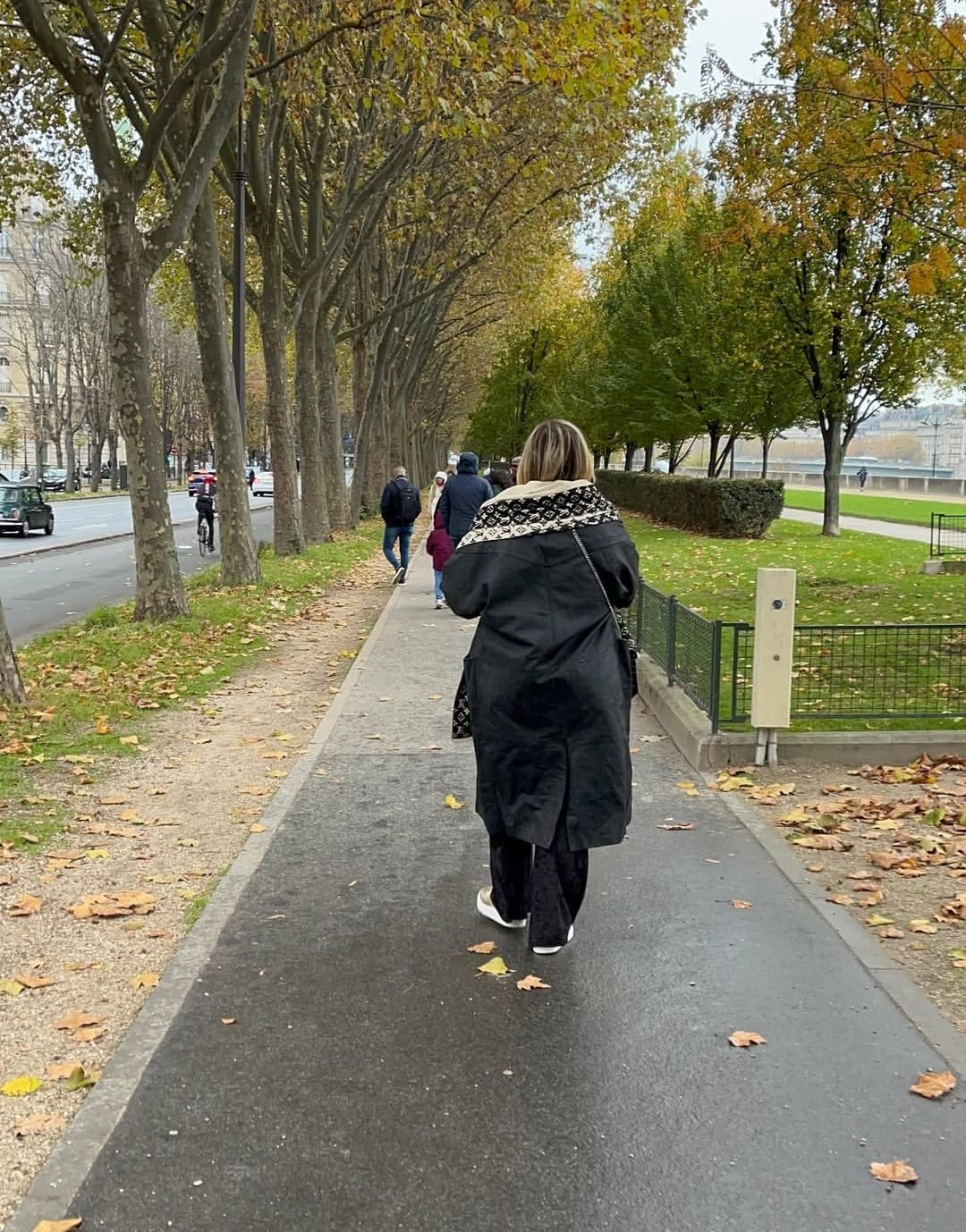 Sandra Martins caminhando por uma alameda arborizada no outono